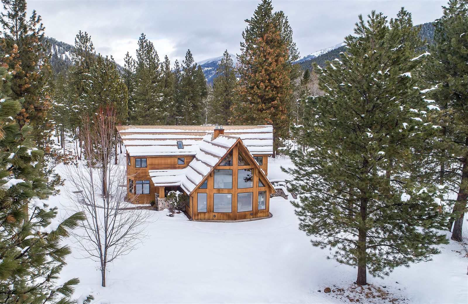 Drone photo of a timber home among snowy pines in Western Montana